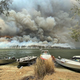 Boats are pulled ashore as smoke and bushfires rage behind Lake Conjola, Australia on January 2, 2020.